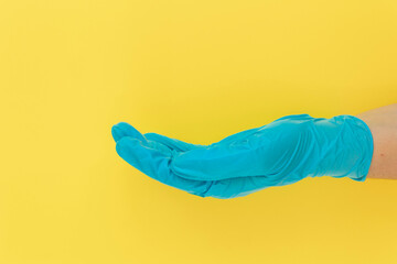 Profile side view of doctor's hand in blue medical (surgical) gloves. Yellow background, copy space.