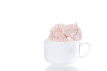 Delicious meringues on a white cup in front of the whita background, isolated, close up