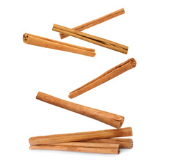 Aromatic cinnamon sticks falling on white background