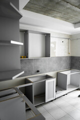 Custom kitchen cabinets installation without a furniture facades mdf. Gray modular kitchen from chipboard material on a various stages of installation in kitchen with a grey tile on floor and walls.
