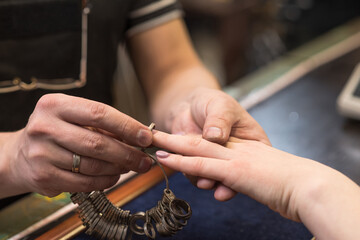 The hands of the jeweler who put the finger ring on the client's hand. Jeweler checks looks the...