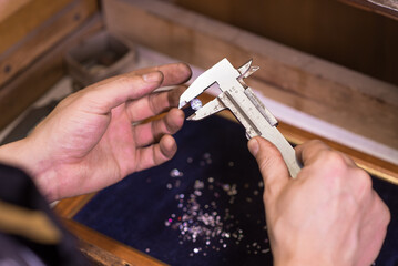 A man jeweler makes an accurate measurement of a gem using a caliper