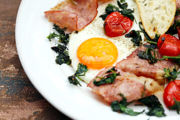 café da manhã de ovos fritos com bacon, verde e cereja, em um prato branco. 