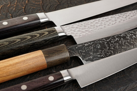 Knife handles and blades close-up on black wooden surface