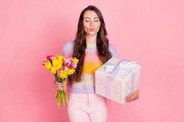 Obraz na płótnie Canvas Portrait of beautiful trendy dreamy girl holding in hands tulips giftbox sending air kiss isolated over pink pastel color background