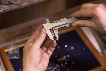 A man jeweler makes an accurate measurement of a gem using a caliper