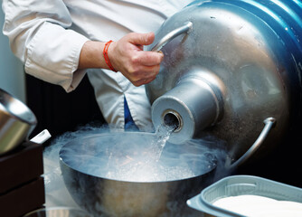 Chef is pouring liquid nitrogen from a large Dewar vessel, toned - obrazy, fototapety, plakaty