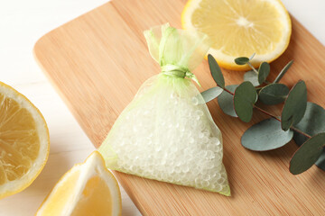 Scented sachet with aroma beads, eucalyptus branch and lemon on white wooden table, closeup