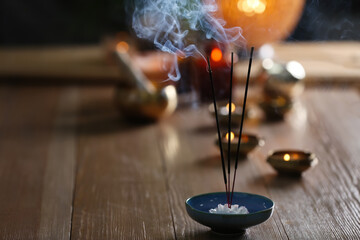 Obraz premium Incense sticks smoldering on wooden table in room. Space for text
