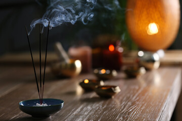 Incense sticks smoldering on wooden table in room. Space for text