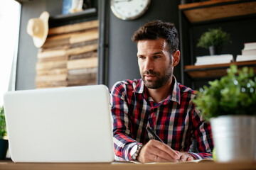 Young businessman working on laptop at office. Businessman sitting at office desk working on new project.