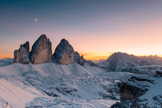 Sunset over Tre Cime di Lavaredo and Monte Cristallo covered with snow in autumn, Dolomites, border of South Tyrol and Veneto
