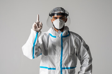 Healthcare doctor man in protective suit and medical mask pointing finger up isolated on white background. Health care concept.