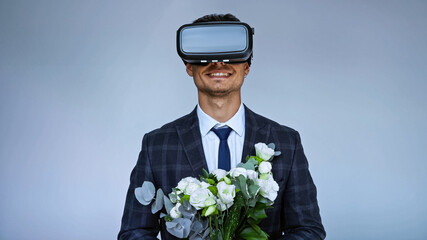 smiling groom in vr headset holding wedding bouquet isolated on blue