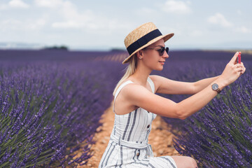 Positive female traveler taking photo of lavender field