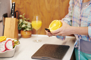 Close-up image of woman cutting fresh orange when preparing plate of snacks when working from home