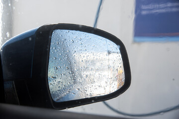 Detalle del retrovisor derecho de un coche cubierto con gotas de agua.