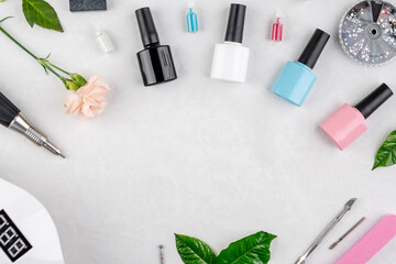 Colorful bottles of nail polishes and tools and accessories for manicure and pedicure procedures on a white background. Top view and copy space
