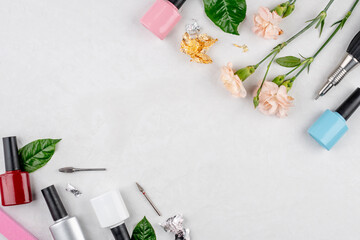 Colorful bottles of nail polishes and tools and accessories for manicure and pedicure procedures on a white background. Top view and copy space