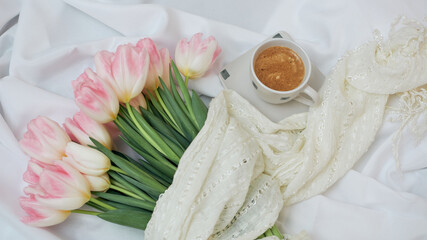 Aromatic morning coffee in a ceramic white cup. Big beautiful bouquet of spring tulips.