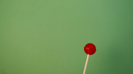red lollipop on a white stick on a turquoise background