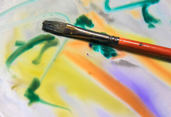 Obraz premium Paint brush on surface of mirror and splashes of colorful watercolor paints.Impressionist abstract artist's work. . High quality photo