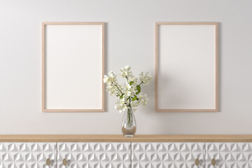 Interior design - sideboard with a glass vase of geranium flowers. Picture frame mockups on the...