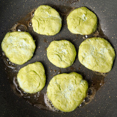seven green cheesecakes with sugar-free cottage cheese in pea flour, fried in a gray pan top view