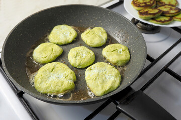 seven green cheesecakes with sugar-free cottage cheese in pea flour, fried in a gray pan side view