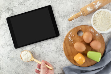 Ingredients and tools for baking and tablet with blank screen and place for text or image on white table. recipe, cookbook, cooking courses online template