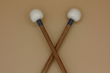 Detail of crossed timpani mallets on a cream background.