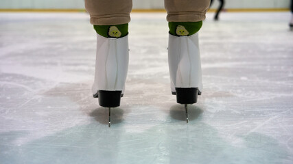 Woman's feet in the ice skates and in funny socks on a winter skating rink.