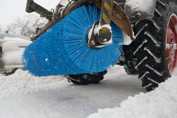 snow removal, urban. Tractor snowplow with a rotary brush and bucket removes snow from the city streets after the storm, clearing the passage for cars