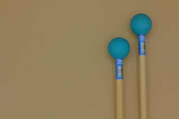 Detail of xylophone mallets in the right side on a cream background.