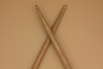 Detail of crossed percussion drumsticks on a cream background.