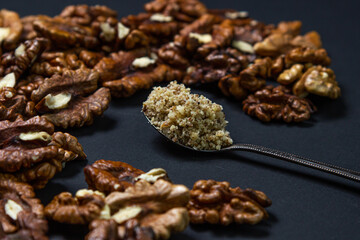 Peeled walnuts and ground walnuts on a black background. A wooden spoon full of ground walnuts. Nutritious food