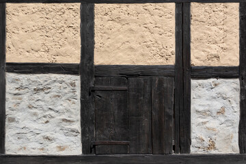 Altes Fachwerk Detail einer Scheune mit kleiner Holztür und verschiedenfarbigem Verputz