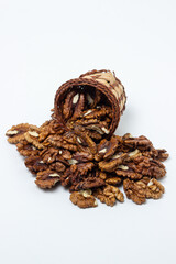 Peeled walnuts on a white background. Peeled walnuts spilled out of the basket. Nutritious food
