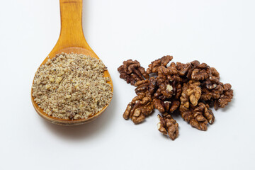Peeled walnuts and ground walnuts on a white background. A wooden spoon full of ground walnuts. Nutritious food