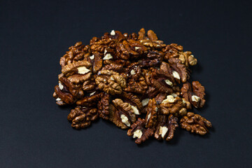 Peeled walnuts on a black background. A bunch of shelled walnuts. Nutritious food