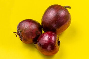 Ripe fruits of red onion on a yellow background