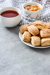 Tasty breakfast. Homemade sweet cinnamon cookies and cup of tea. Apple confiture on background