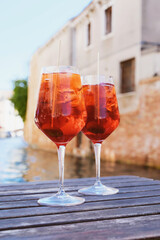 Two glasses of Spritz Veneziano cocktail served near the Venetian canal.  Popular italian summer aperitif drink.