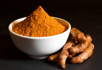 Turmeric powder and fresh turmeric (curcumin) on black background,spices.