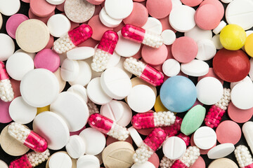 Background of assorted pharmaceutical capsules and medication in different colors.