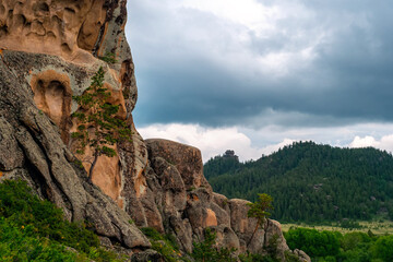 Rocky cliff of unusual rocks with pine trees. Hardened lava of ancient volcanoes. Mountains of Kent. Kazakhstan