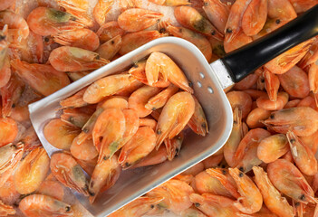 Sale of frozen shrimp. Close-up of frozen shrimp. Shrimp and scoop at a fish market or shop, top view.