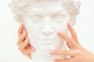 Women's hands gently touch the cheek of the sculpture of a man.Creative concept.Contemporary Art.