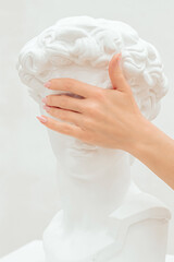 A woman's hand covers the eyes of a plastic sculpture of a man.Creative concept.