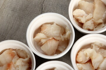several dishes with raw fresh fish pieces before frying. dishes with unroasted julienne. Sliced white fish fillet in white pots 